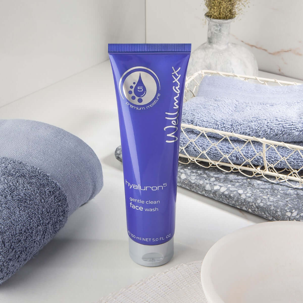 hyaluron⁵ gentle clean face wash in a purple tube with towels, promoting radiant skin and moisture retention.