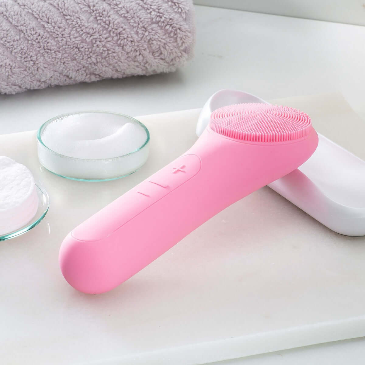 LiFTmee PEEL and CLEAN tool in pink, featuring silicone bristles and buttons for skincare cleaning and exfoliating.