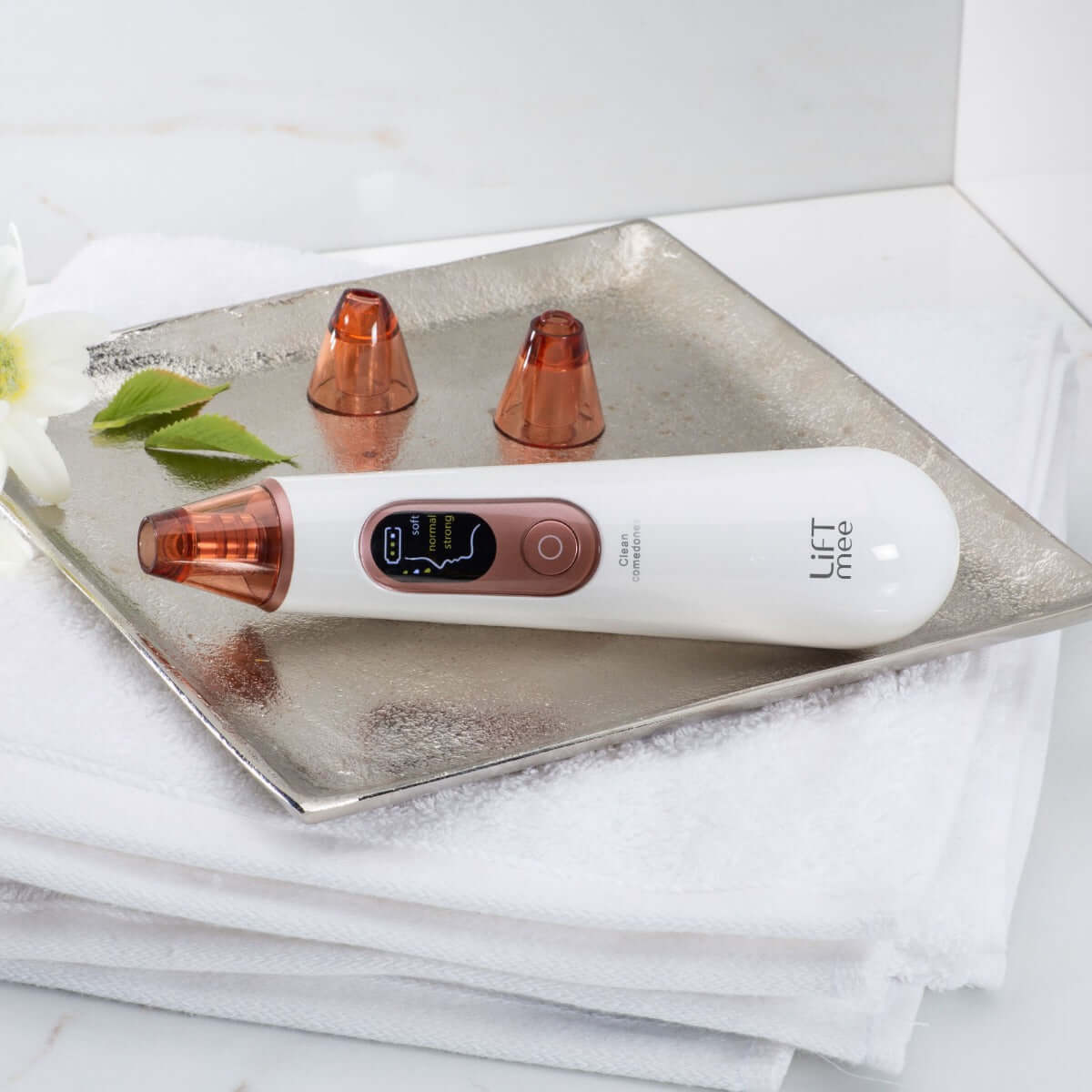 LiFTmee SKIN OPTIMIZER device on a silver tray with replacement tips, designed for gentle blackhead removal and skin rejuvenation.