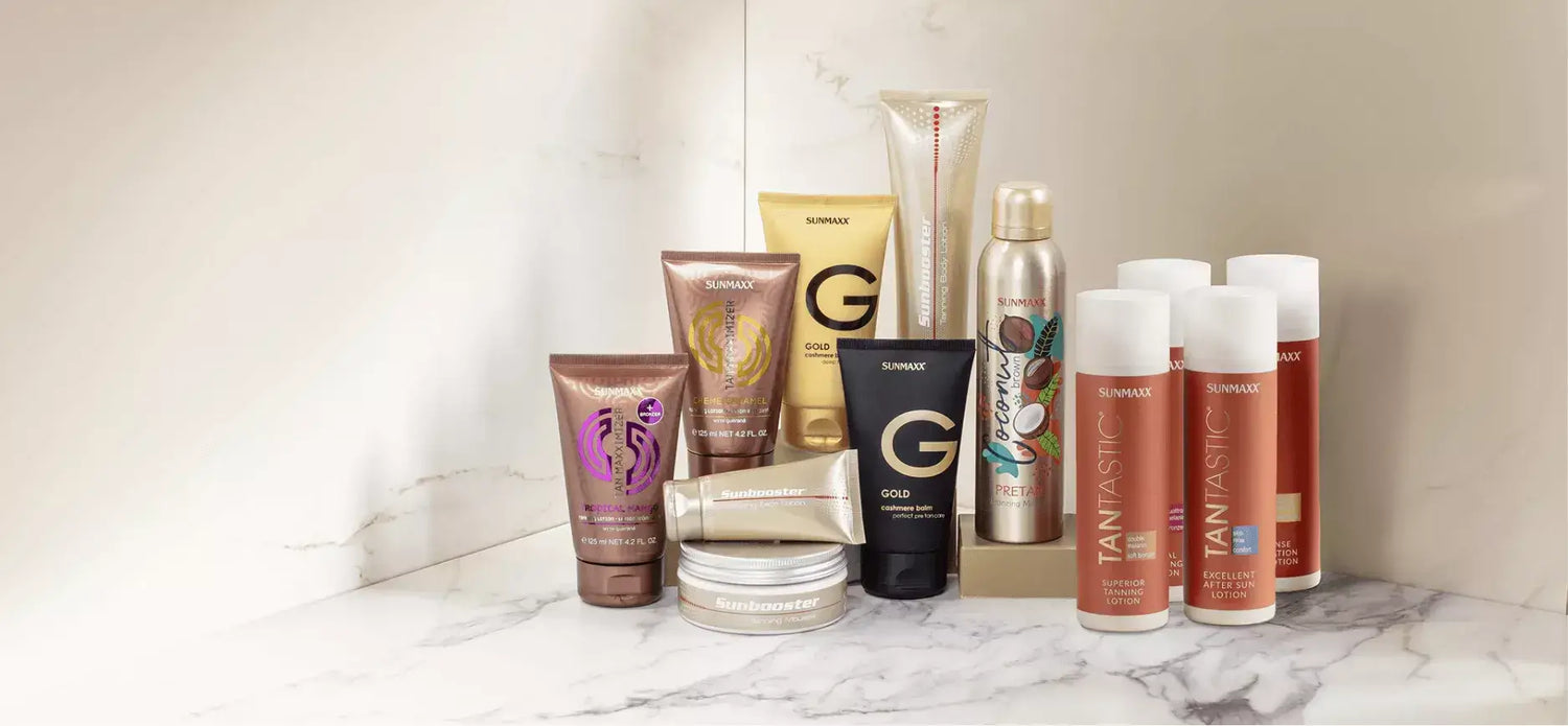 A collection of various tanning and skincare products arranged on a marble surface.
