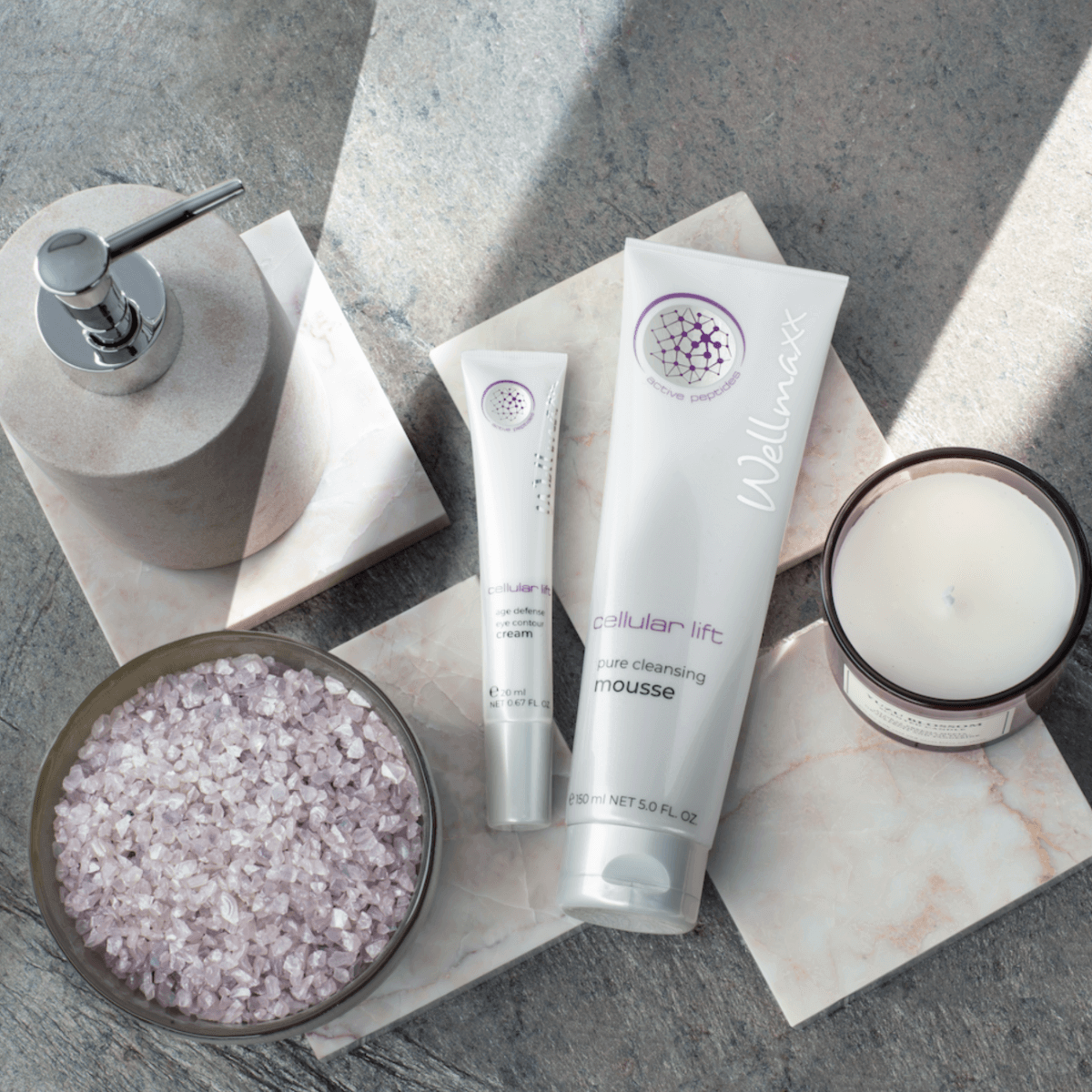 Cellular Lift Pure Cleansing Mousse displayed with skincare products, bath salts, and a candle for a spa-like ambiance.