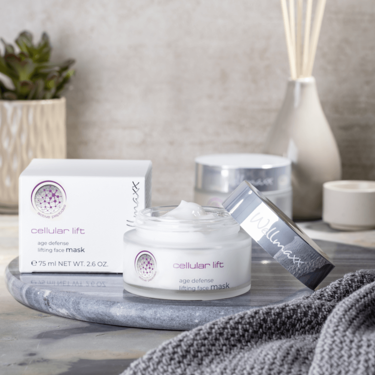 cellular lift age defense lifting face mask cream jar and packaging on a marble surface with decorative items