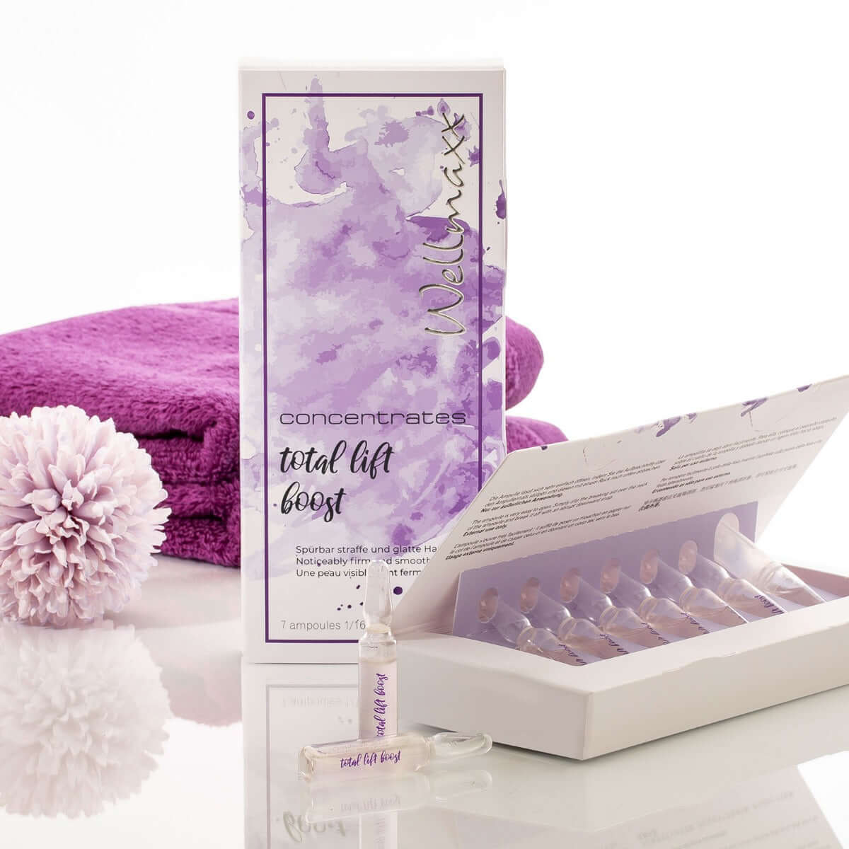 Wellmax Concentrates Total Lift Boost packaging and ampoule with towels and decor elements for enhanced skincare.