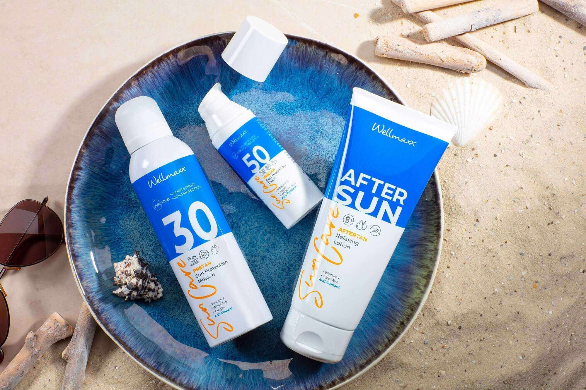 Sunscreen and after-sun products from Wildman in a decorative bowl on a sandy beach.