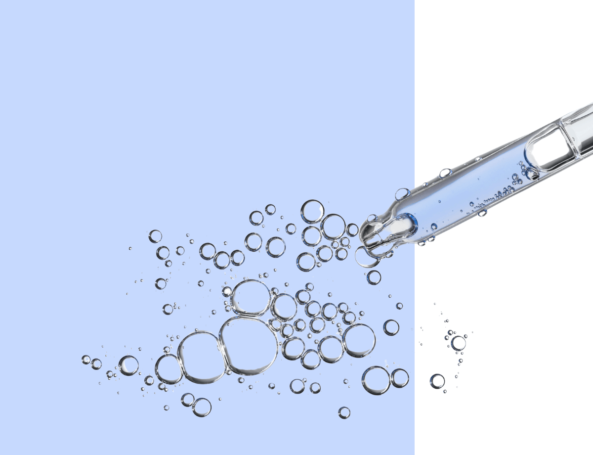 Close-up of a pipette dispensing liquid with bubbles against a blue background.