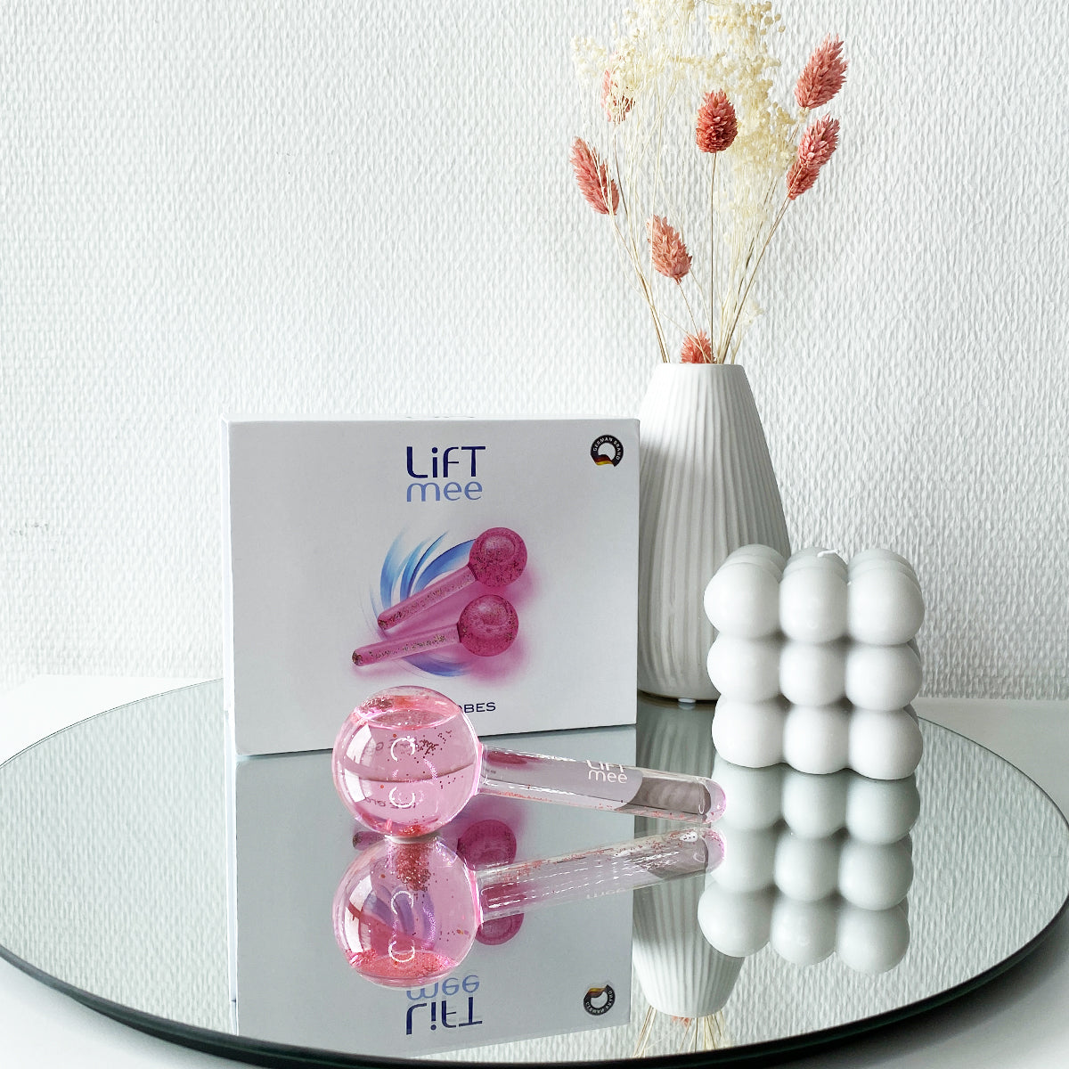 LiFTmee ICE GLOBES Duo Set in pink, placed on a mirroe with a vase and box, ideal for facial massage and skincare.