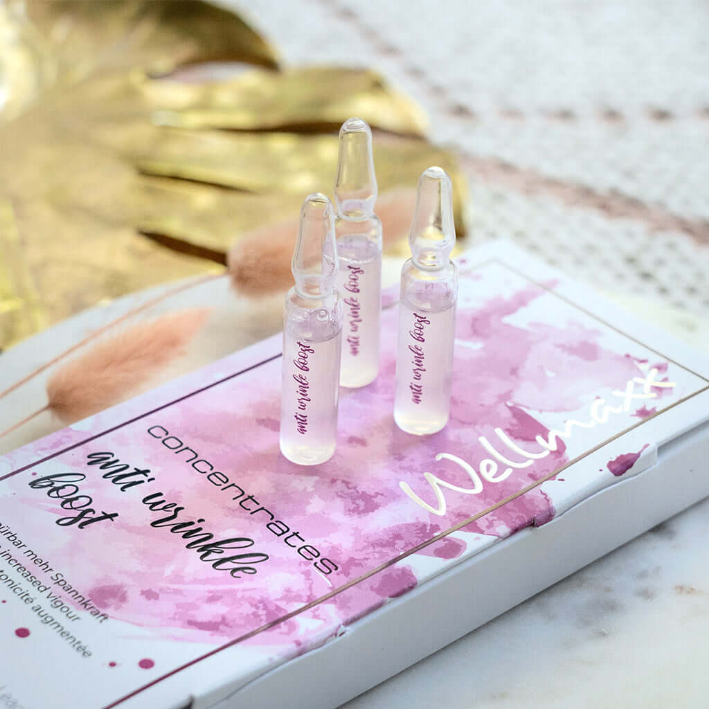 Anti-wrinkle boost concentrates with hyaluronic acid in elegant packaging, featuring ampoules and floral accents.